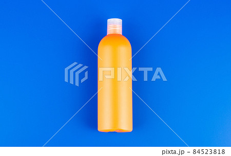 orange shampoo bottle on blue background, toiletries 84523818