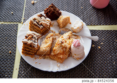 Leftovers in a plate on the table with sweets cakes, close-up Leftovers in a plate on the table with sweets cakes, close-up 84524356
