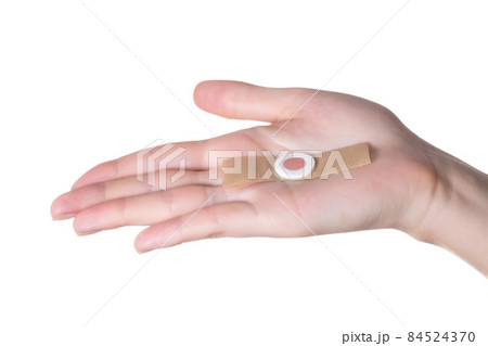 A woman's hand holds a medical plaster against core calluses on the soles of the feet. Close-up, isolate A woman's hand holds a medical plaster against core calluses on the soles of the feet. Close-up, isolate 84524370