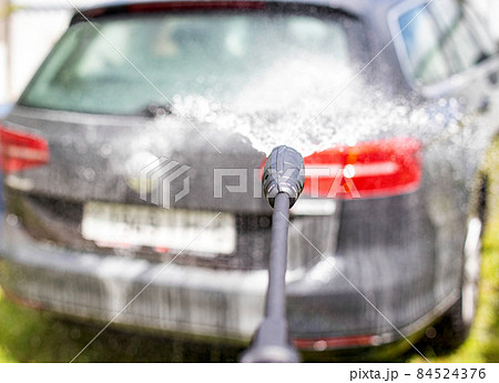 Washing a gray modern car with a manual pressure washer in a summer cottage. Car shampoo for cleaning dirt, transport 84524376