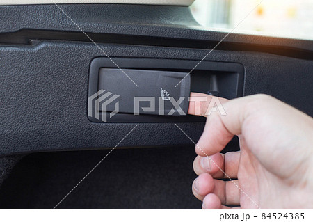 Button for folding and unfolding the rear row of seats in a passenger car, close-up 84524385