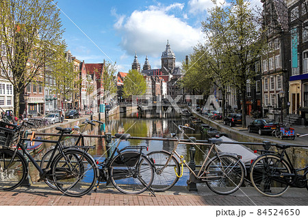Amsterdam city with bikes on bridge against old cathedral during springtime in Netherlands. Amsterdam city with bikes on bridge against old cathedral during springtime in Netherlands. 84524650