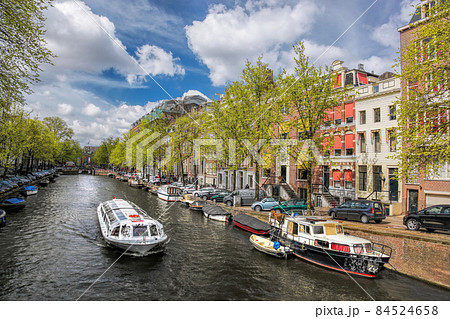 Amsterdam city with tourist boats on canal during springtime in Netherlands. 84524658
