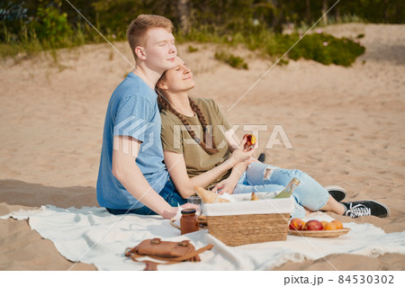 Picnic on beach with food and drinks. Young boy and girl sunbathing 84530302