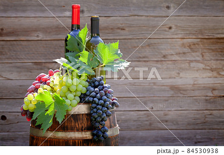 Various colorful grapes and wine bottles on wine barrel Various colorful grapes and wine bottles on wine barrel 84530938