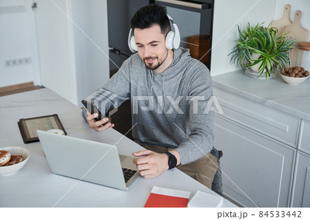 Caucasian man sitting at table at home and using his laptop during the online conference 84533442