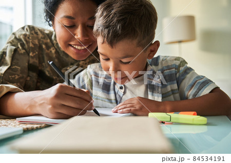 Black mother writing with her schoolboy son Black mother writing with her schoolboy son 84534191