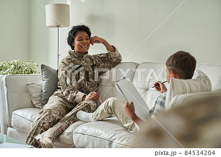 Black boy drawing in notebook with mother on couch 84534204