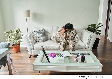 Black mother soldier reading book with son at home Black mother soldier reading book with son at home 84534205
