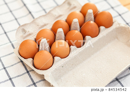 A few brown eggs among the cells of a large cardboard bag, a chicken egg as a valuable nutritious product, a tray for carrying and storing fragile eggs. A full package of eggs, an important food item A few brown eggs among the cells of a large cardboard bag, a chicken egg as a valuable nutritious product, a tray for carrying and storing fragile eggs. A full package of eggs, an important food item 84534542