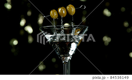 Freeze motion of falling olives into martini drink Freeze motion of falling olives into martini drink 84536149