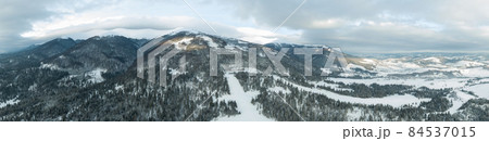 Aerial shot of majestic sunrise in the mountains. Valley between the mountains is covered with fog and is illuminated by the warm rays of the rising sun. Mountains covered with forest natural. Aerial shot of majestic sunrise in the mountains. Valley between the mountains is covered with fog and is illuminated by the warm rays of the rising sun. Mountains covered with forest natural. 84537015