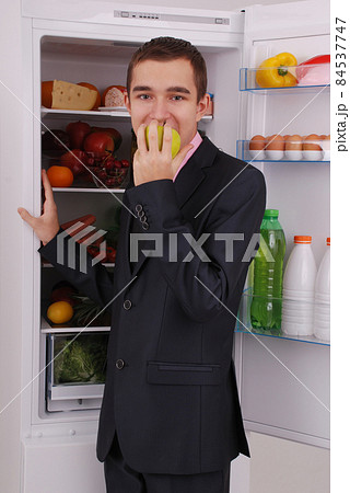 Teenager boy in suit and tie near the refrigerator 84537747