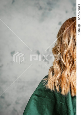 Rear View of a woman with long brown hair against a gray background. 84537884