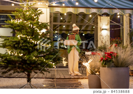 New Year's decorated backyard with a woman walking with presents New Year's decorated backyard with a woman walking with presents 84538688
