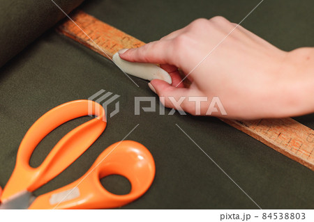 tailor marks up textile using soap and wooden ruler on pattern cutting tailor marks up textile using soap and wooden ruler on pattern cutting 84538803