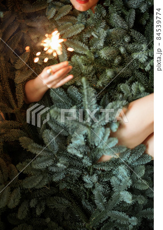 Woman with sparkler covered with nobilis branches Woman with sparkler covered with nobilis branches 84539774