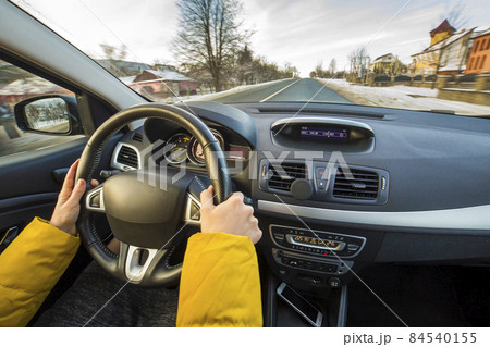 Modern car interior with driver female hands on steering wheel, winter snowy landscape outside. Safe driving concept. 84540155