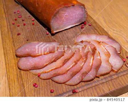 Sliced smoked gammon on a wooden table with addition of fresh herbs and aromatic spices. Sliced smoked gammon on a wooden table with addition of fresh herbs and aromatic spices. 84540517