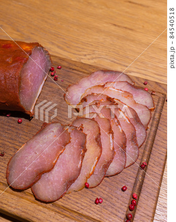 Sliced smoked gammon on a wooden table with addition of fresh herbs and aromatic spices. 84540518