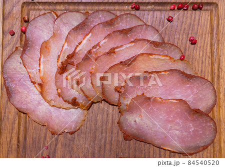 Sliced smoked gammon on a wooden table with addition of fresh herbs and aromatic spices. Sliced smoked gammon on a wooden table with addition of fresh herbs and aromatic spices. 84540520