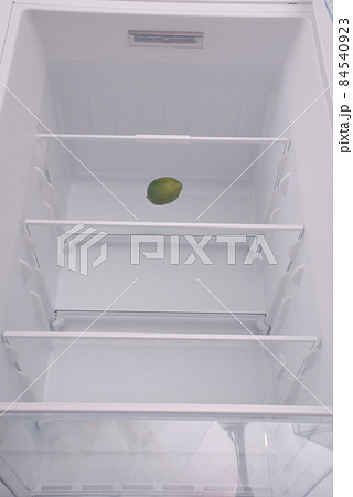 One lemon in open empty refrigerator. One lemon in open empty refrigerator. 84540923