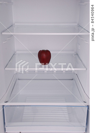 One apple in open empty refrigerator. One apple in open empty refrigerator. 84540964