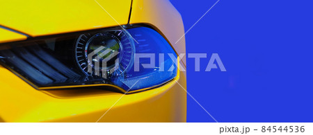 Close-up front headlight with xenon light on yellow sport car on blue color background Close-up front headlight with xenon light on yellow sport car on blue color background 84544536