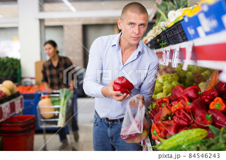 Man choosing red pepper in greengrocer Man choosing red pepper in greengrocer 84546243