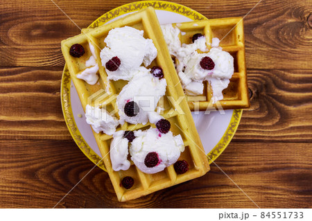 Belgian waffles with ice cream and blackberries on wooden table Belgian waffles with ice cream and blackberries on wooden table 84551733