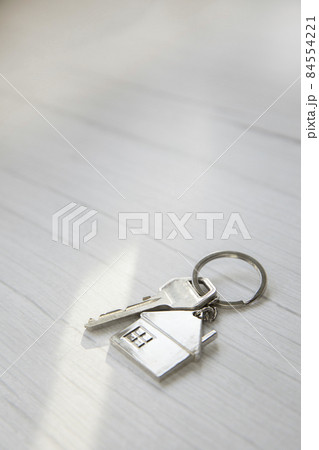 Silver key with silver house figure on white wooden background, buying new house real estate concept copy space 84554221