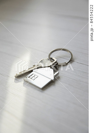 Silver key with silver house figure on white wooden background, buying new house real estate concept copy space 84554222