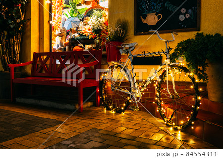 A bicycle decorated for the Christmas holidays on a night street. A bicycle decorated for the Christmas holidays on a night street. 84554311