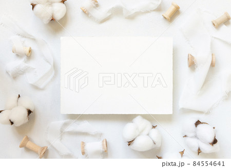 Blank card on white table with cotton flowers top view Blank card on white table with cotton flowers top view 84554641