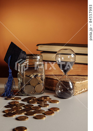 Jar with coins, graduation hat and hourglass. Savings and education theme Jar with coins, graduation hat and hourglass. Savings and education theme 84557993