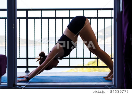Young fitness woman doing morning yoga practice at the balcony near the sea 84559775
