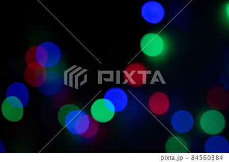Defocused bokeh lights on black background, an abstract naturally blurred backdrop for Christmas eve or birthday party. Festive light texture. Colorful garland in blur. Overlay effect for design 84560384