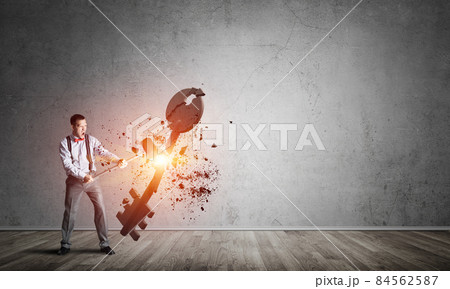 Breaking through access concept with man in room crashing concrete key Breaking through access concept with man in room crashing concrete key 84562587