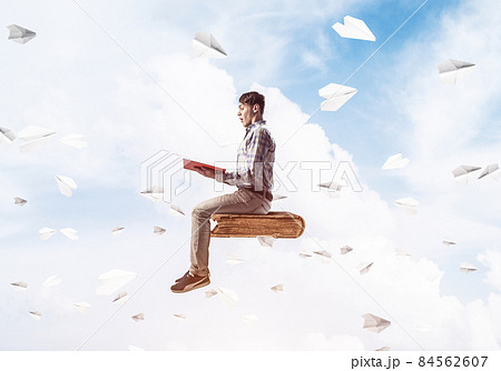Handsome man student reading book and paper planes flying around 84562607