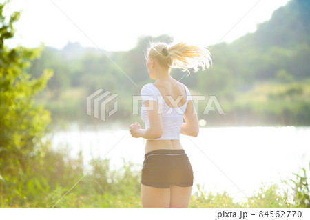 Young beautiful woman running shows press stomach workout training wearing top. 84562770