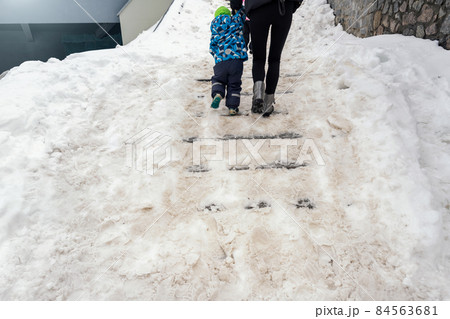 People walk by concrete stone staircase covered dirty deep slippery snow after blizzard snowstorm snowfall at city pedestrian walkway. Slide fall injury danger slip steps. Winter cold season weather People walk by concrete stone staircase covered dirty deep slippery snow after blizzard snowstorm snowfall at city pedestrian walkway. Slide fall injury danger slip steps. Winter cold season weather 84563681