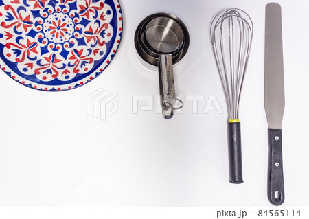 Kitchen utensils, measuring cups, whisk , and spatula on white background with copy space Kitchen utensils, measuring cups, whisk , and spatula on white background with copy space 84565114