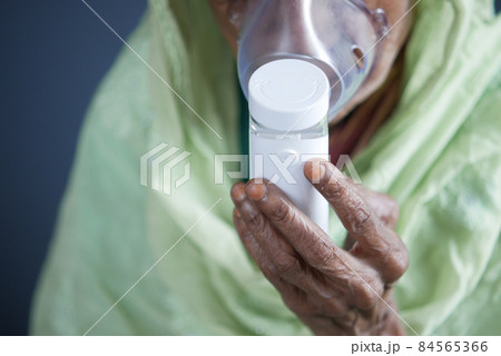 senior women hand hold a nebulizer against light gray background senior women hand hold a nebulizer against light gray background 84565366