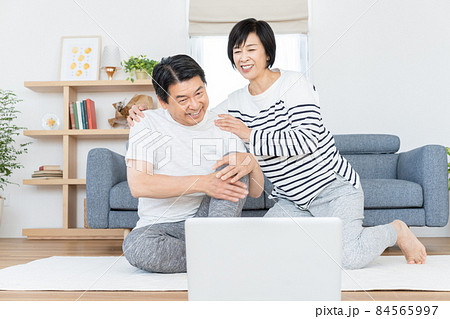 自宅のリビングでオンラインで体操をするミドルエイジの夫婦 84565997