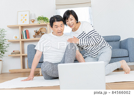 自宅のリビングでオンラインで体操をするミドルエイジの夫婦 84566002