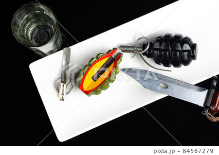 Hand grenades on a plate with rifles bayonet and glass of vodka. Military concept. Hand grenades on a plate with rifles bayonet and glass of vodka. Military concept. 84567279