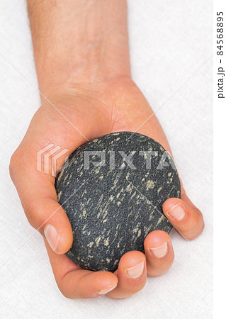 Hand of masseur holding massage stone on white background, top view. Hand of masseur holding massage stone on white background, top view. 84568895