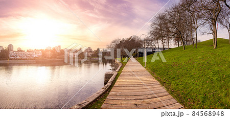 Wooden path in a modern city park during sunny fall season. 84568948