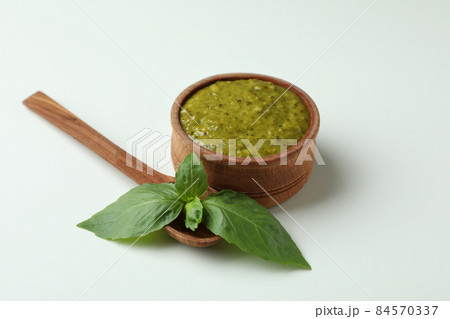 Bowl of Pesto sauce, basil and spoon on white background Bowl of Pesto sauce, basil and spoon on white background 84570337