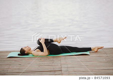 Woman practicing advanced yoga by the water 84571093